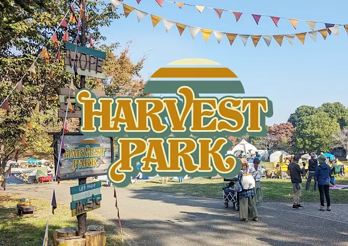 広い芝生の公園に重ねられたHARVEST PARKのロゴのバナー